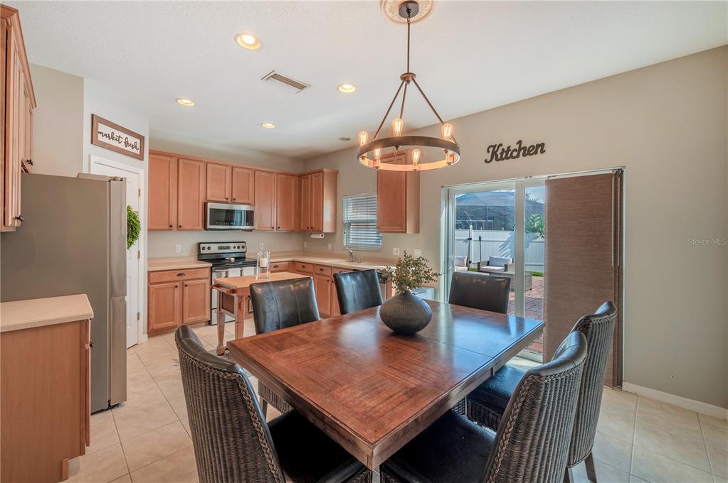 Kitchen and dining area with warm wood cabinets, a large table, and a sliding glass door to the patio.