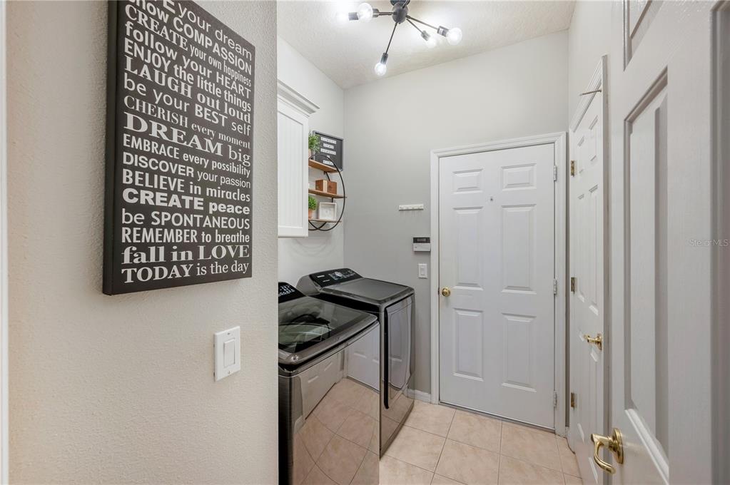 Laundry room with washer and dryer, tile floor, and a large inspirational sign.