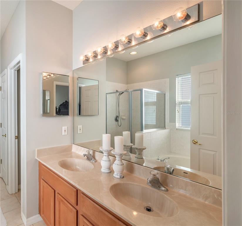 Bathroom with a double-sink vanity, large mirrors, and a glass-enclosed shower.