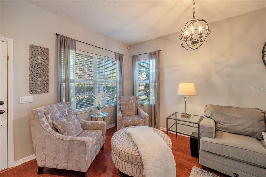 Living room with patterned armchairs, a gray sofa, and large shuttered windows.