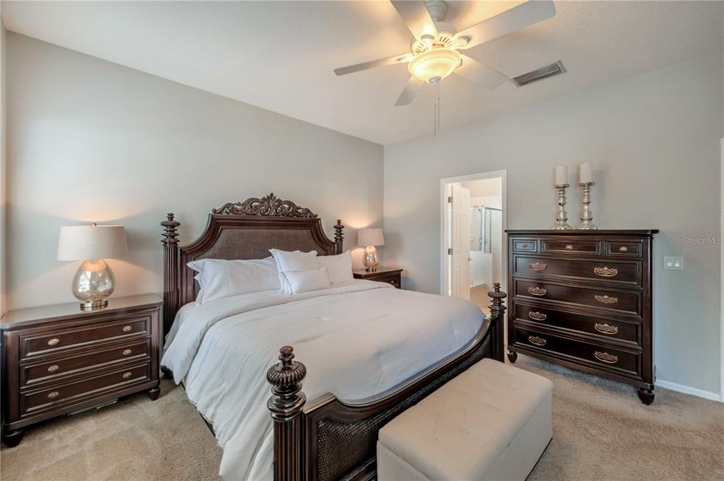 Bedroom with a dark wood bed, white bedding, matching furniture, and a ceiling fan.