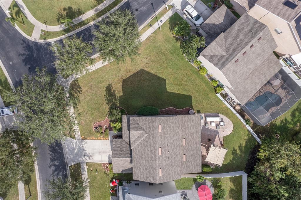 Aerial view of a single-story home with a broad lawn, patio, and covered outdoor structure.
