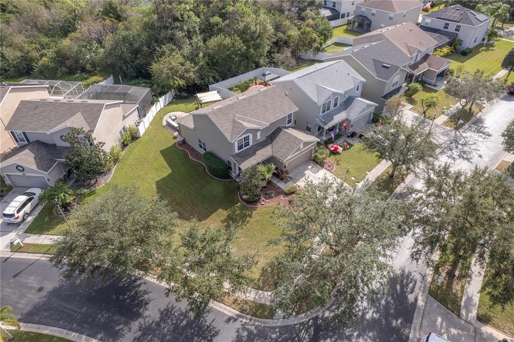 Aerial view of a gray two-story house with a broad lawn and landscaped front yard.
