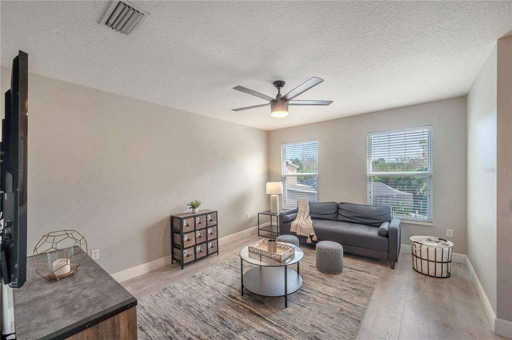 Staged living room with a gray sofa between two windows and a round coffee table.