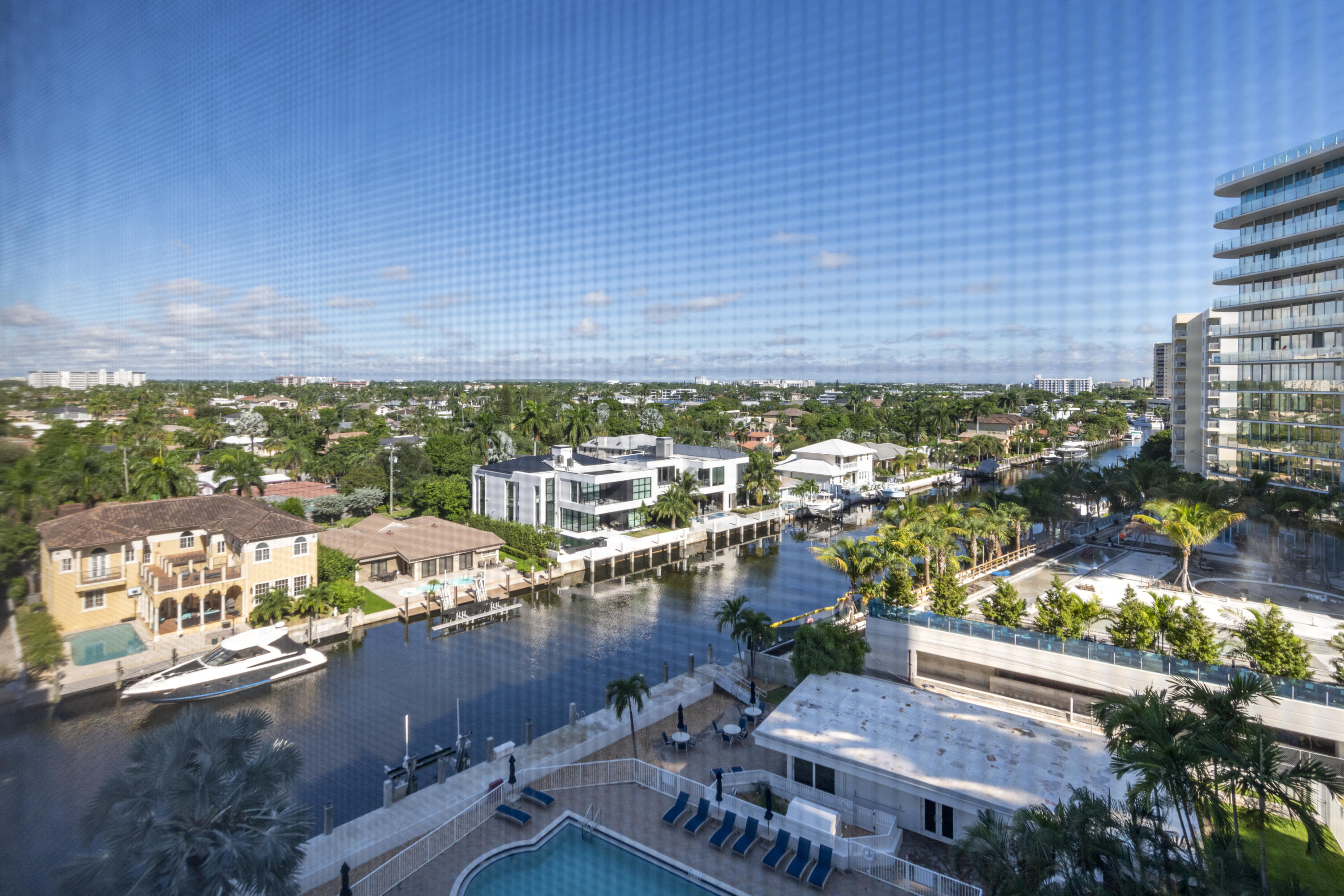 Waterfront canal and homes viewed from a high-rise, with a pool in the foreground.
