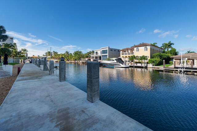 Concrete dock beside a canal, with a boat and waterfront homes across the water.