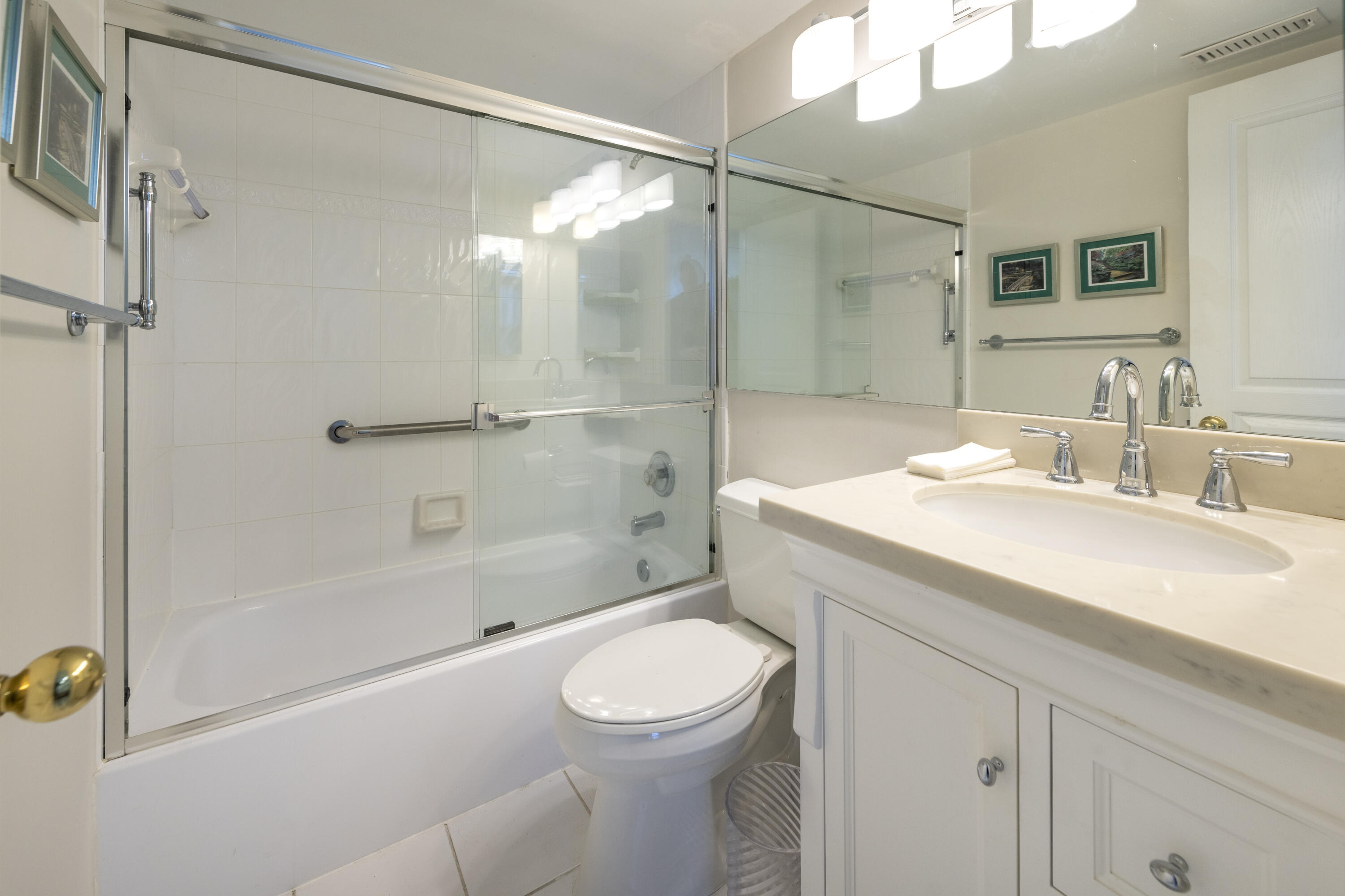 Bathroom with a glass-enclosed tub and shower beside a white vanity and sink.