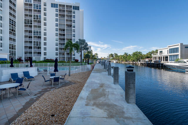 Condominium grounds beside a canal, with a waterfront walkway, outdoor seating, and boats.