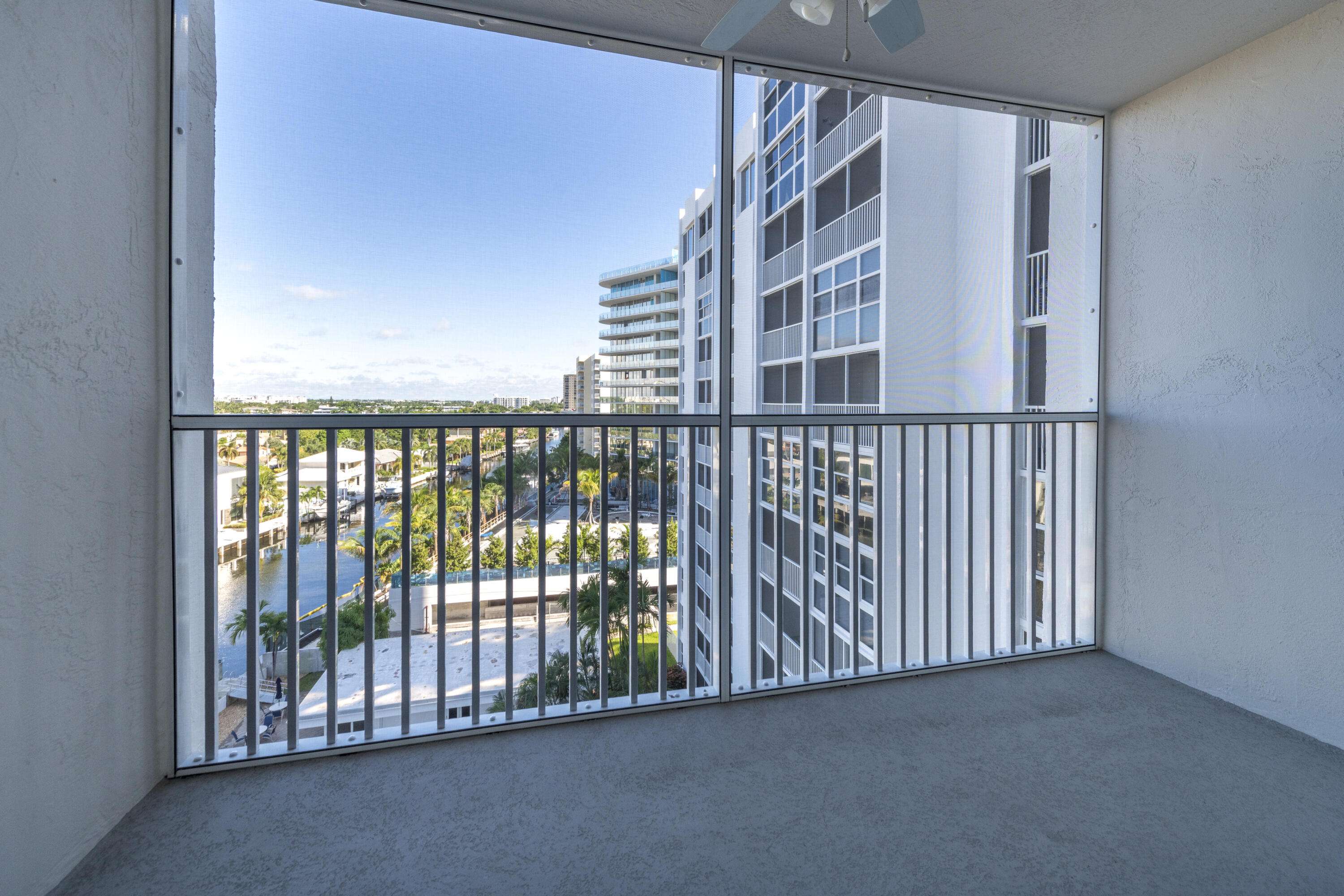 Condo balcony overlooking a palm-lined canal and neighboring high-rise buildings.