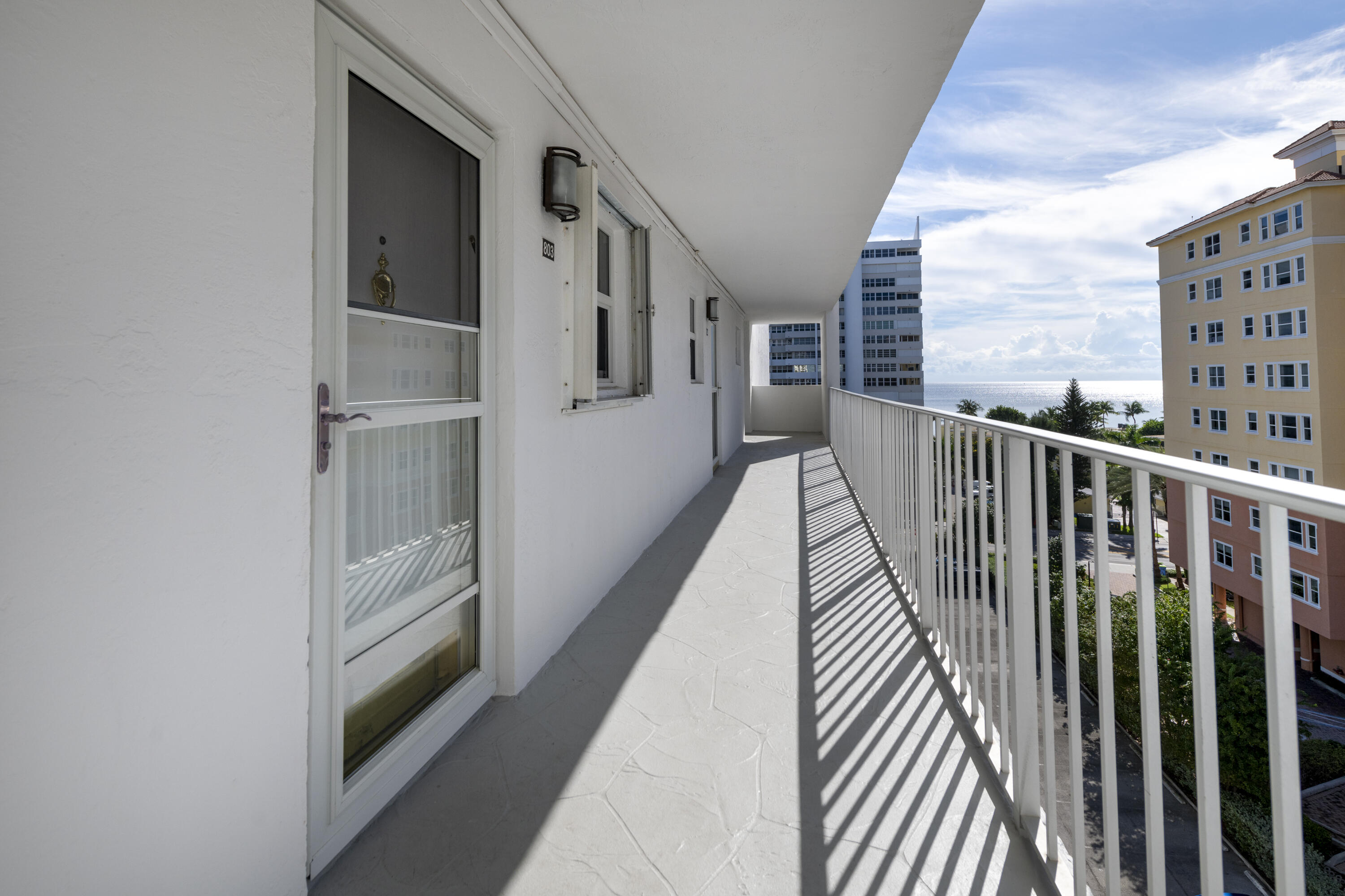 Condo balcony with ocean view, white railing, and unit 803 entrance.