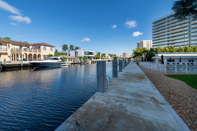 Waterfront dock beside a canal, with a moored boat and condominium buildings along the shore.