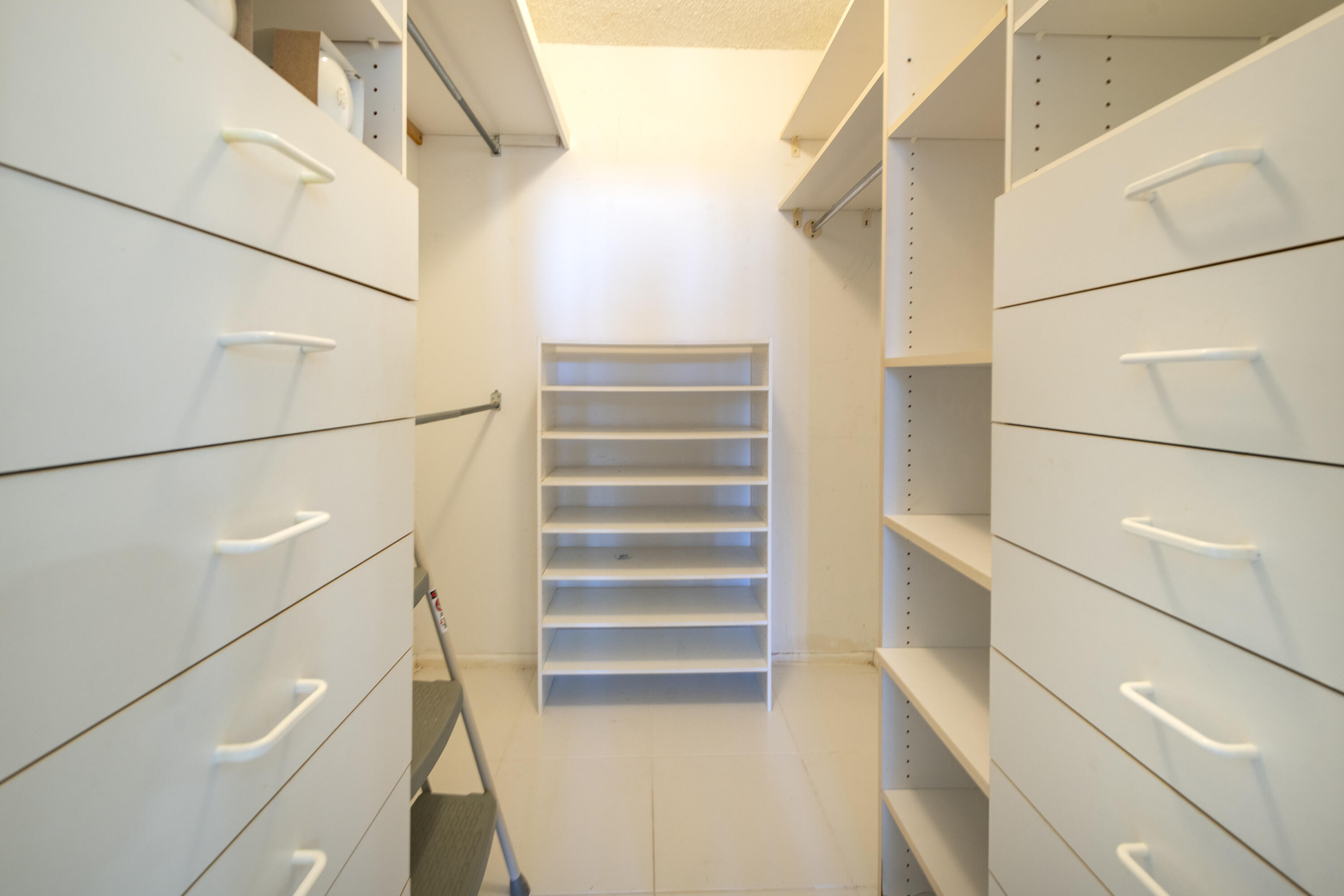Walk-in closet with built-in drawers on both sides and open shelving at the back.