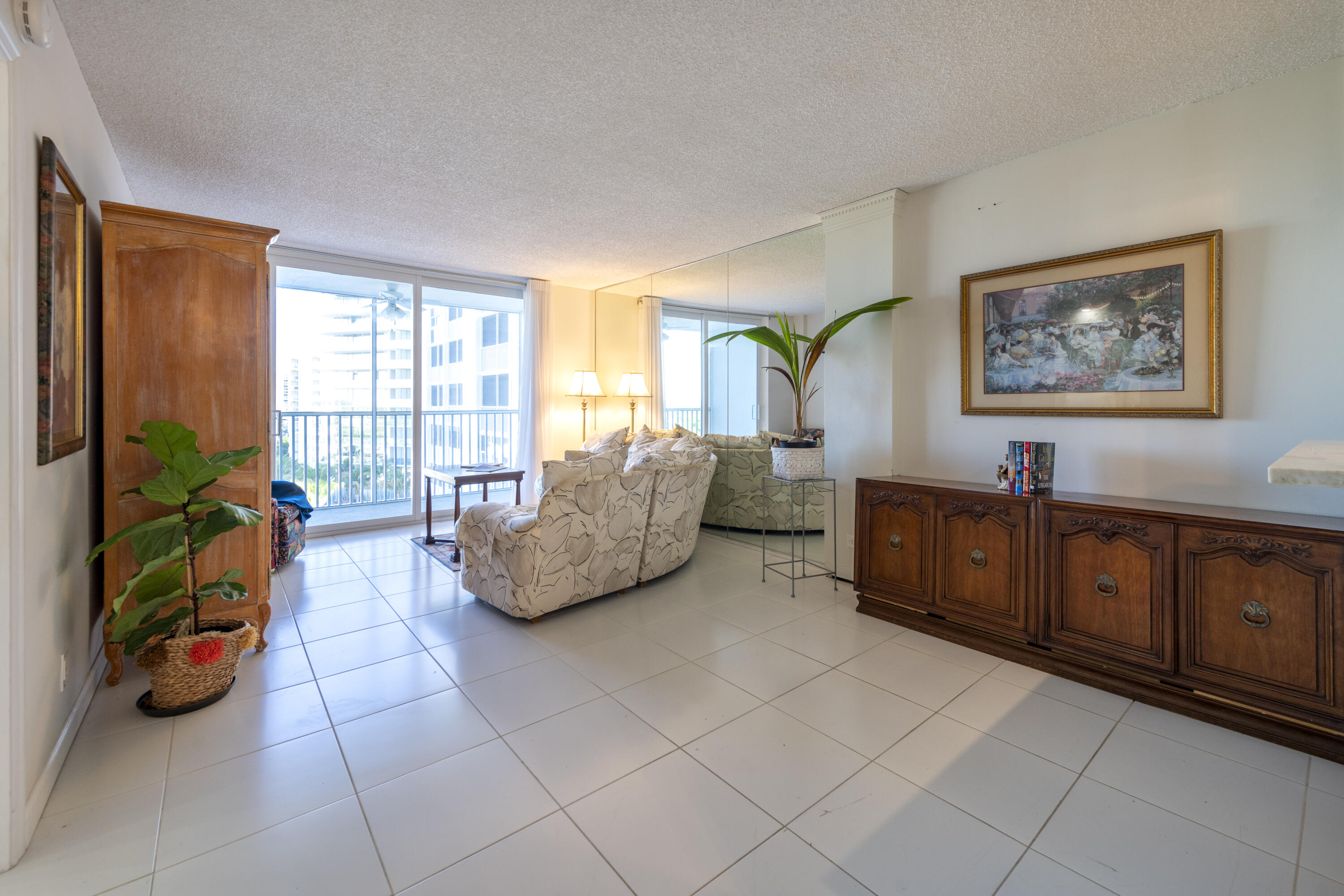 Condominium living room with cream sofas, a carved wooden sideboard, and sliding doors to a balcony.