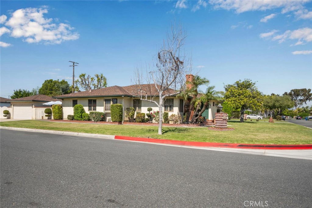 Single-story house on a landscaped corner lot, with an attached garage and red-painted curb.