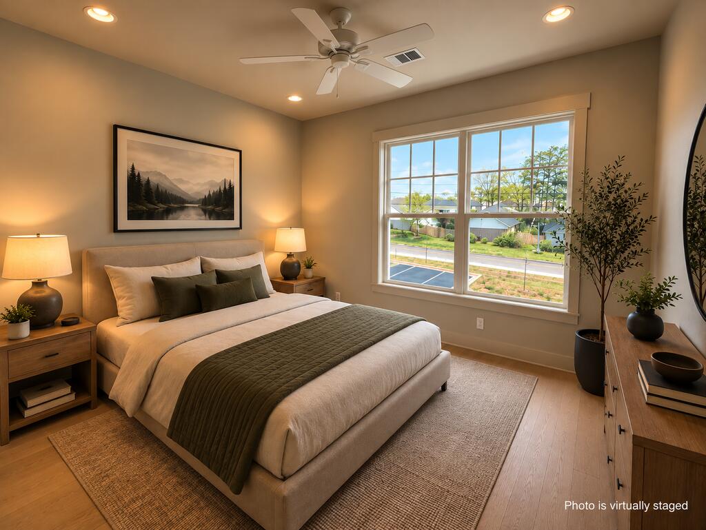 Bedroom with a white bed, dark green bedding, and a large street-facing window.
