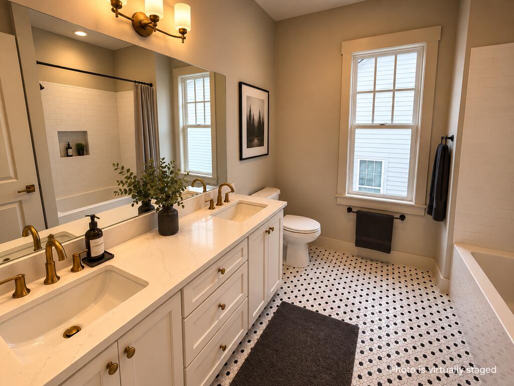 Bathroom with a double vanity, brass fixtures, and black-and-white hexagonal floor tile.