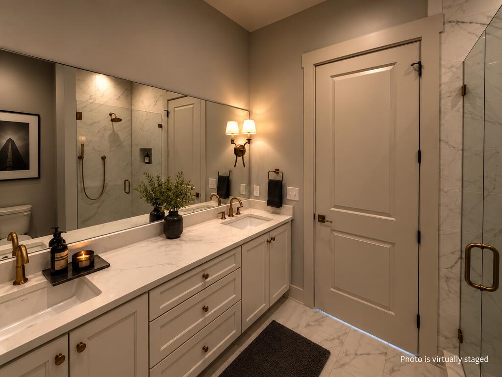Bathroom with a marble vanity, brass fixtures, and a glass-enclosed marble shower.