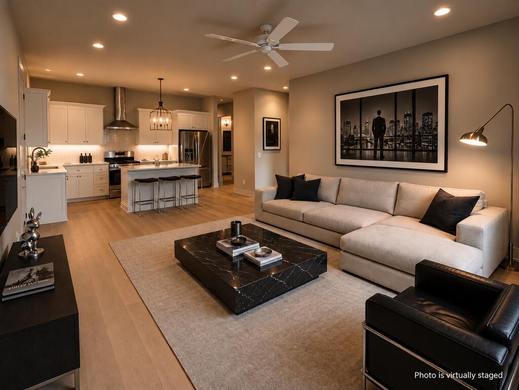Open-plan living room and kitchen with a light sectional, marble coffee table, and white cabinetry; virtually staged.