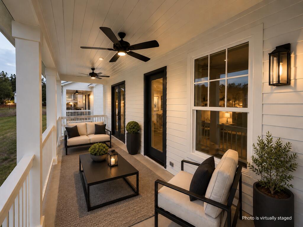 Covered porch with ceiling fans, white siding, and virtually staged lounge seating.