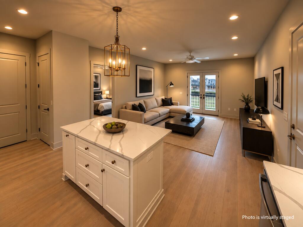 Open-plan kitchen and living room with a large island, beige sofa, and glass doors to a balcony.