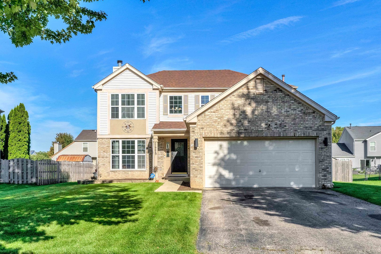 Two-story brick-and-siding home with an attached double garage and green front lawn.