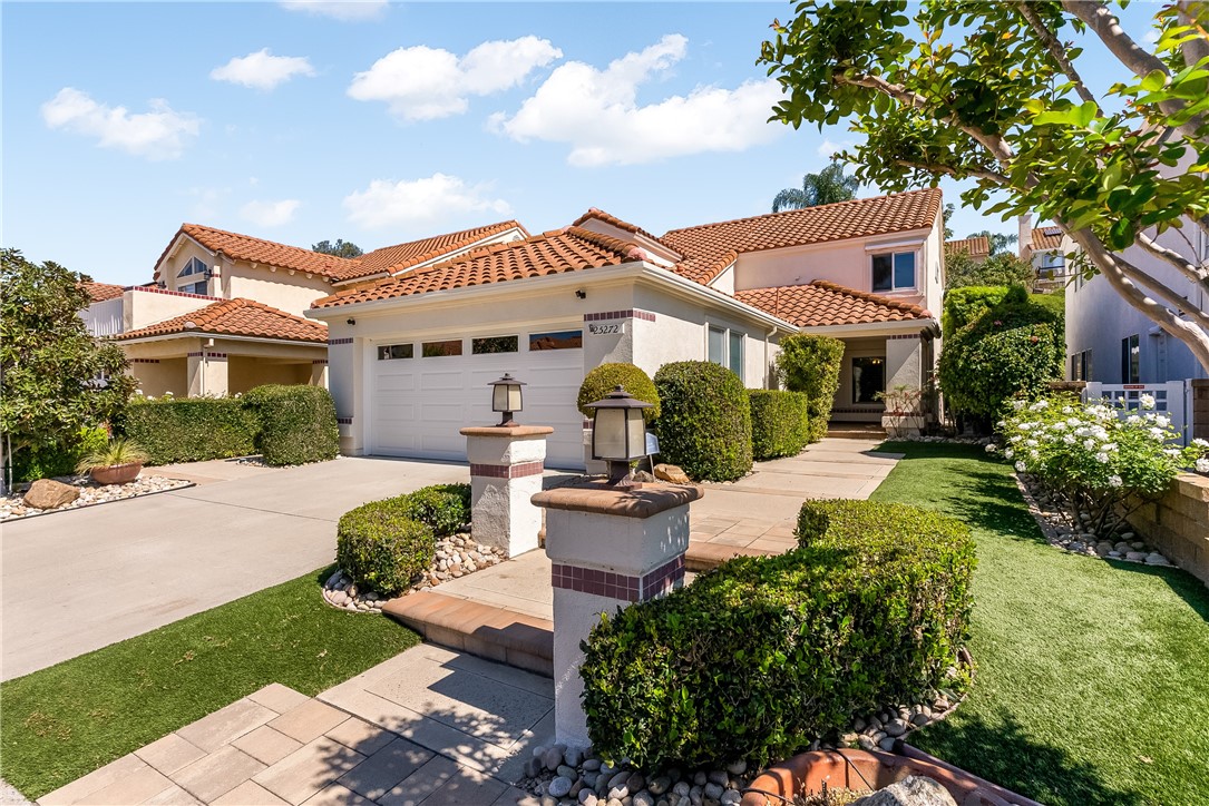 Two-story stucco home with terracotta tile roof, double garage, and landscaped front yard.