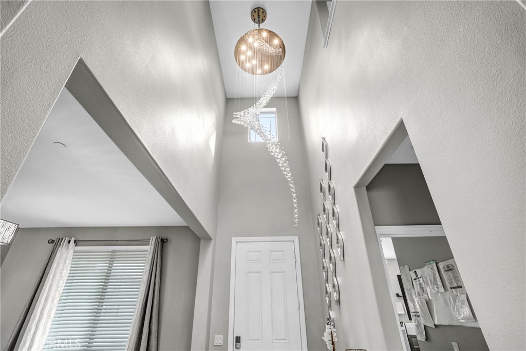 Tall entry foyer with a cascading crystal chandelier, clerestory window, and white double front doors.