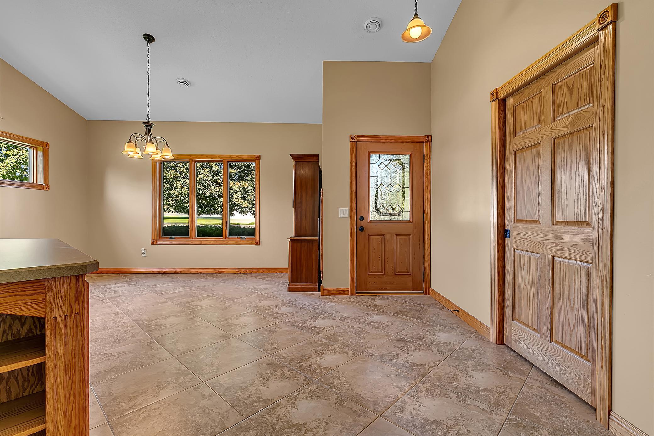 Entryway with a tiled floor, decorative-glass front door, wood trim, and large windows.