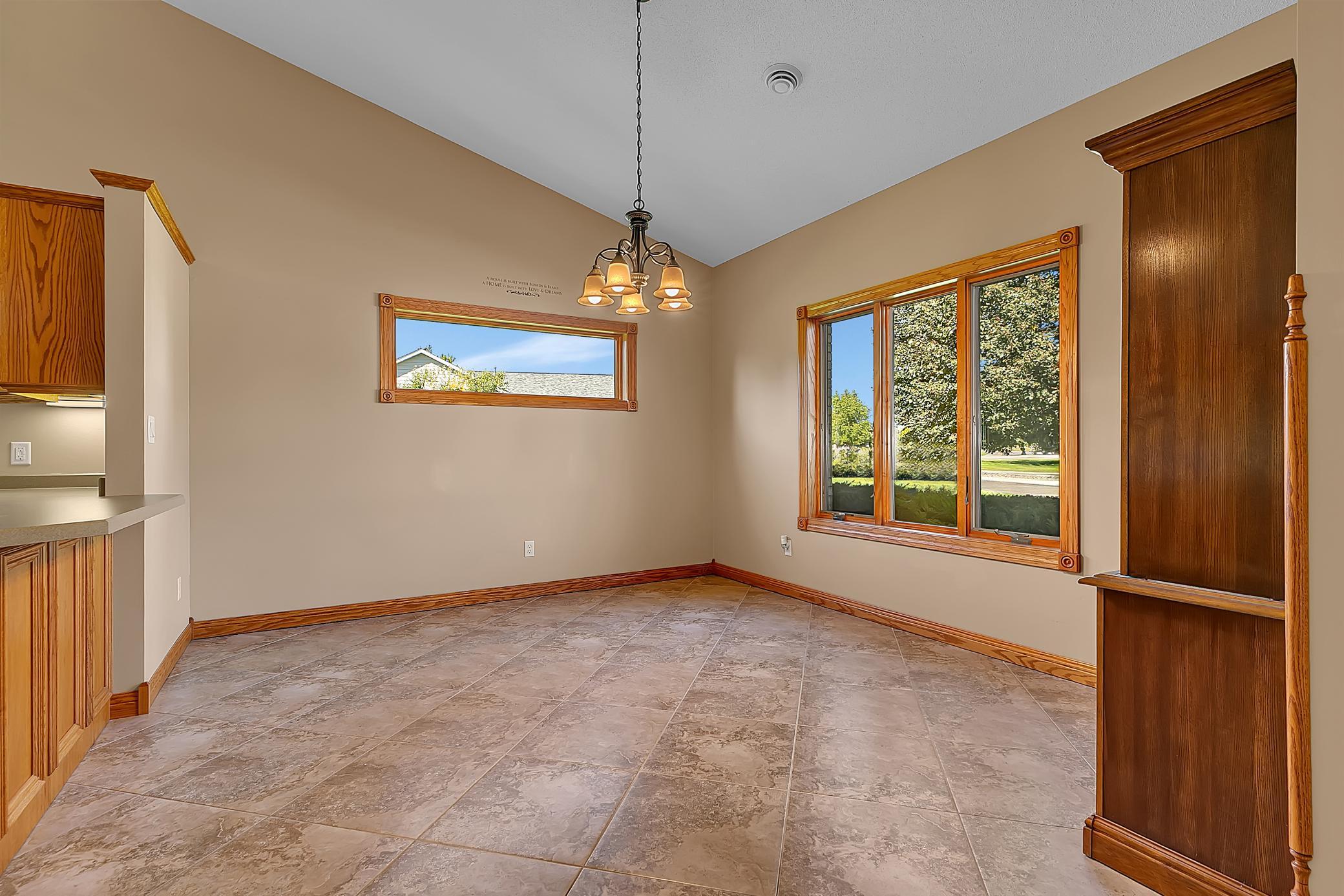 Empty dining room with tiled floors, wood trim, a chandelier, and large windows.