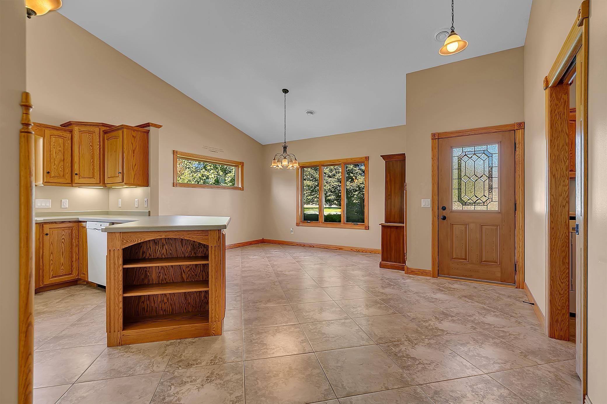 Kitchen and dining area with a wood island, tiled floors, and a decorative glass entry door.