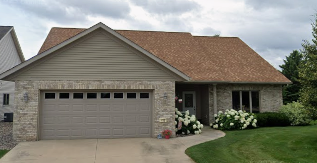 Brick house with a two-car garage and white hydrangeas along the front walkway.