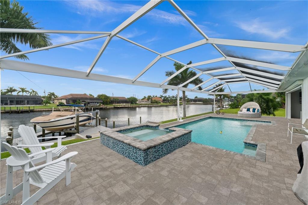 Canal-side pool and raised spa beneath a screened lanai, with a boat docked nearby.