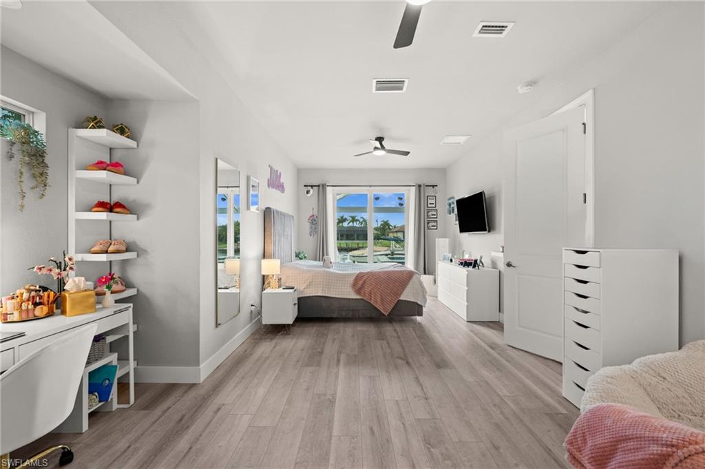 Bedroom with gray flooring, white furnishings, and sliding glass doors overlooking the water.