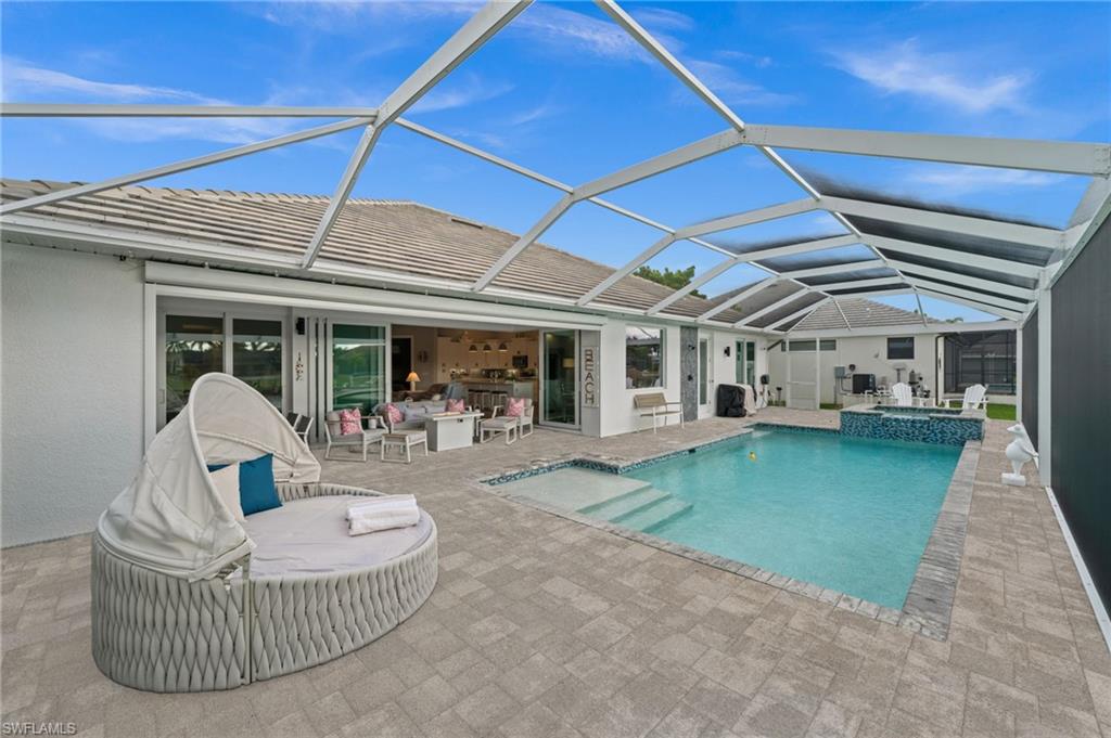 Pool and tiled lanai with lounge seating beneath a screened enclosure.
