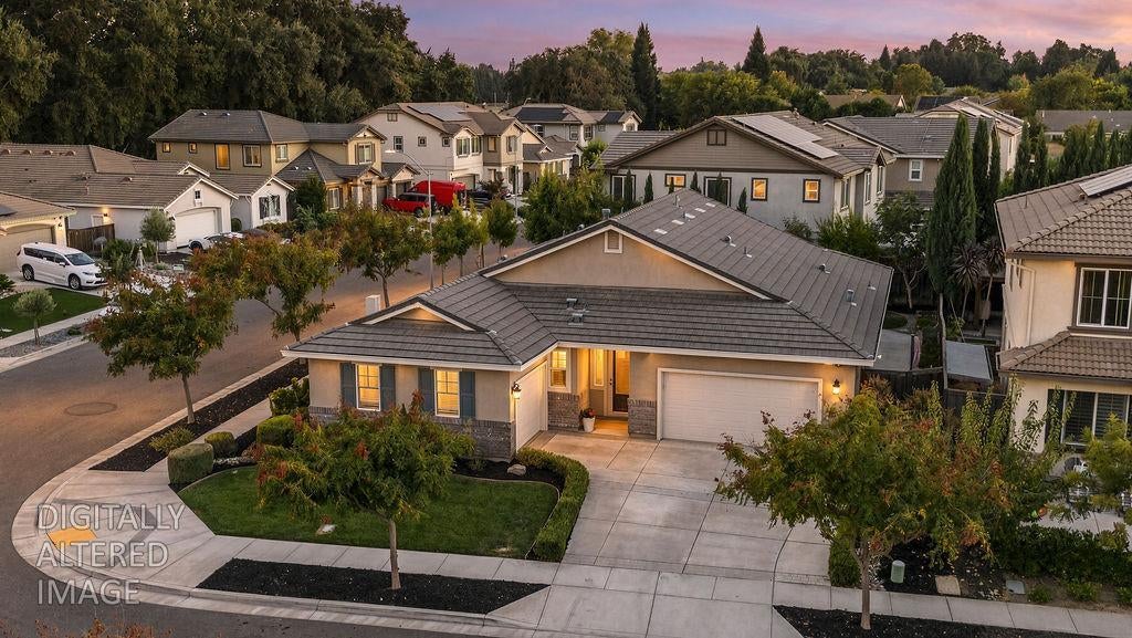 Single-story home with a gray tile roof, attached garage, and landscaped front yard, viewed from above.