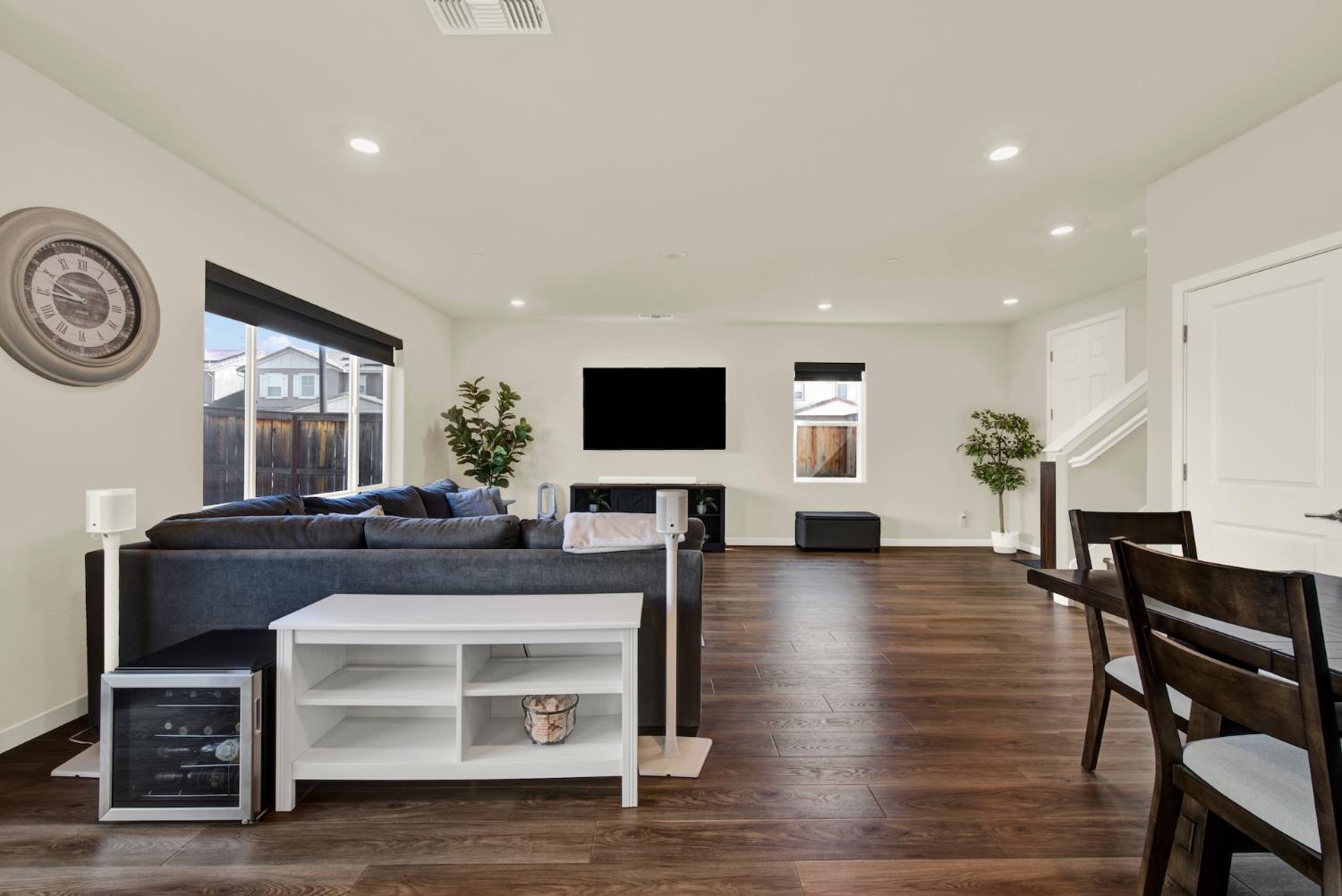 Furnished living room with dark wood floors, sectional sofa, and wall-mounted television.