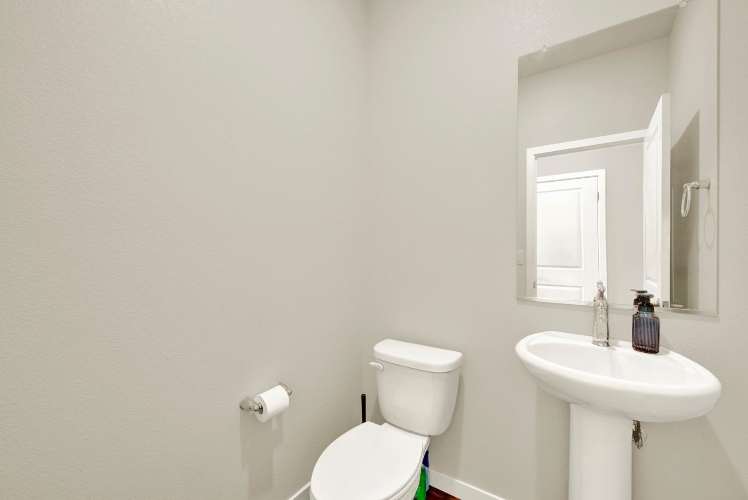 Bathroom with a white pedestal sink, toilet, and large wall mirror.