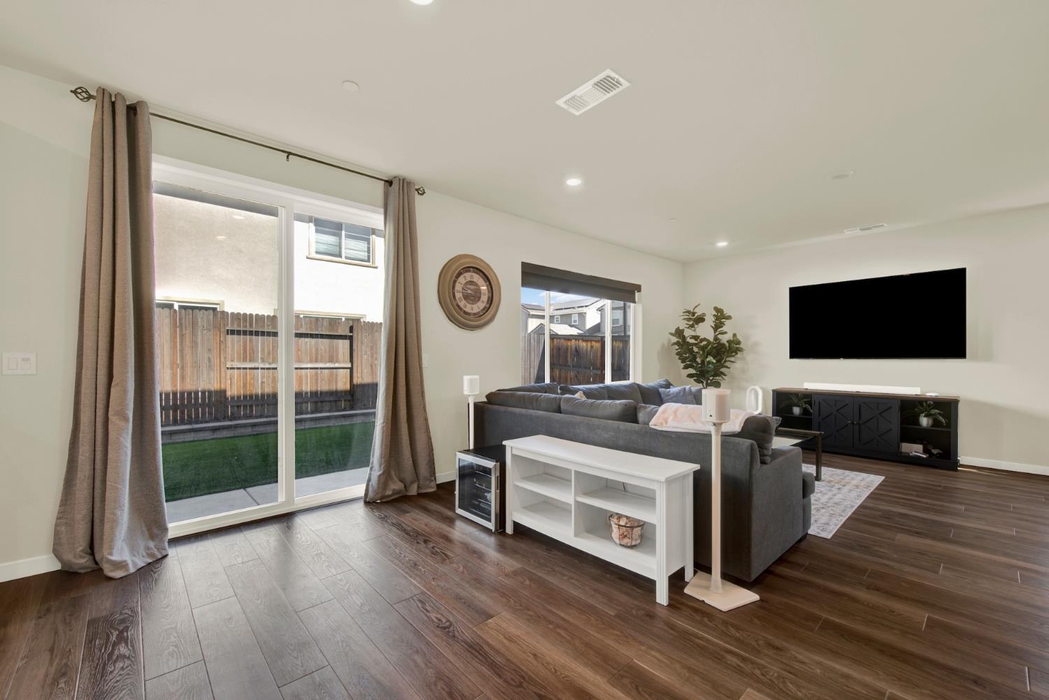 Living room with a gray sectional, wall-mounted television, and sliding doors to the backyard.