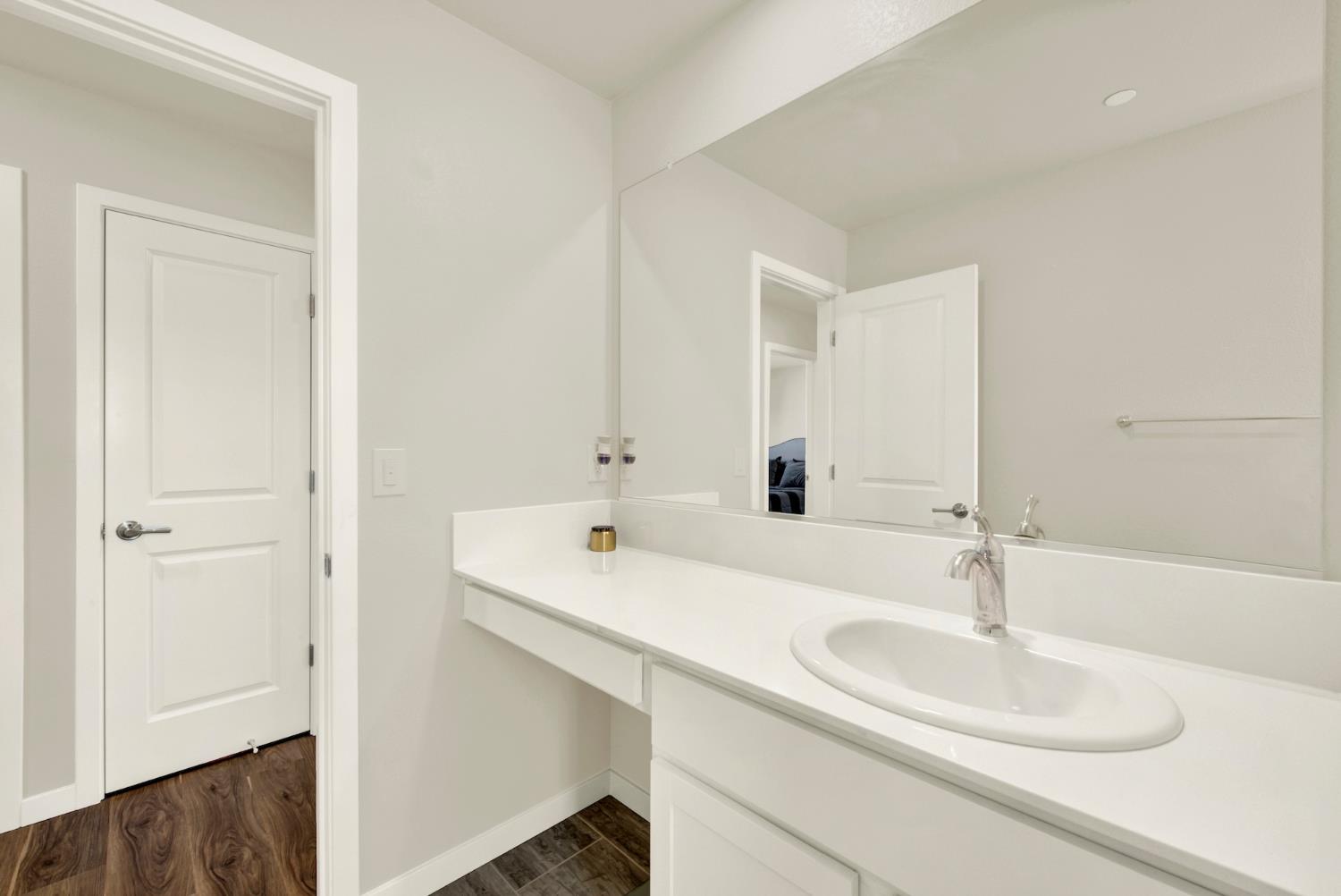 Bathroom vanity with a large mirror, white countertop, and oval sink.