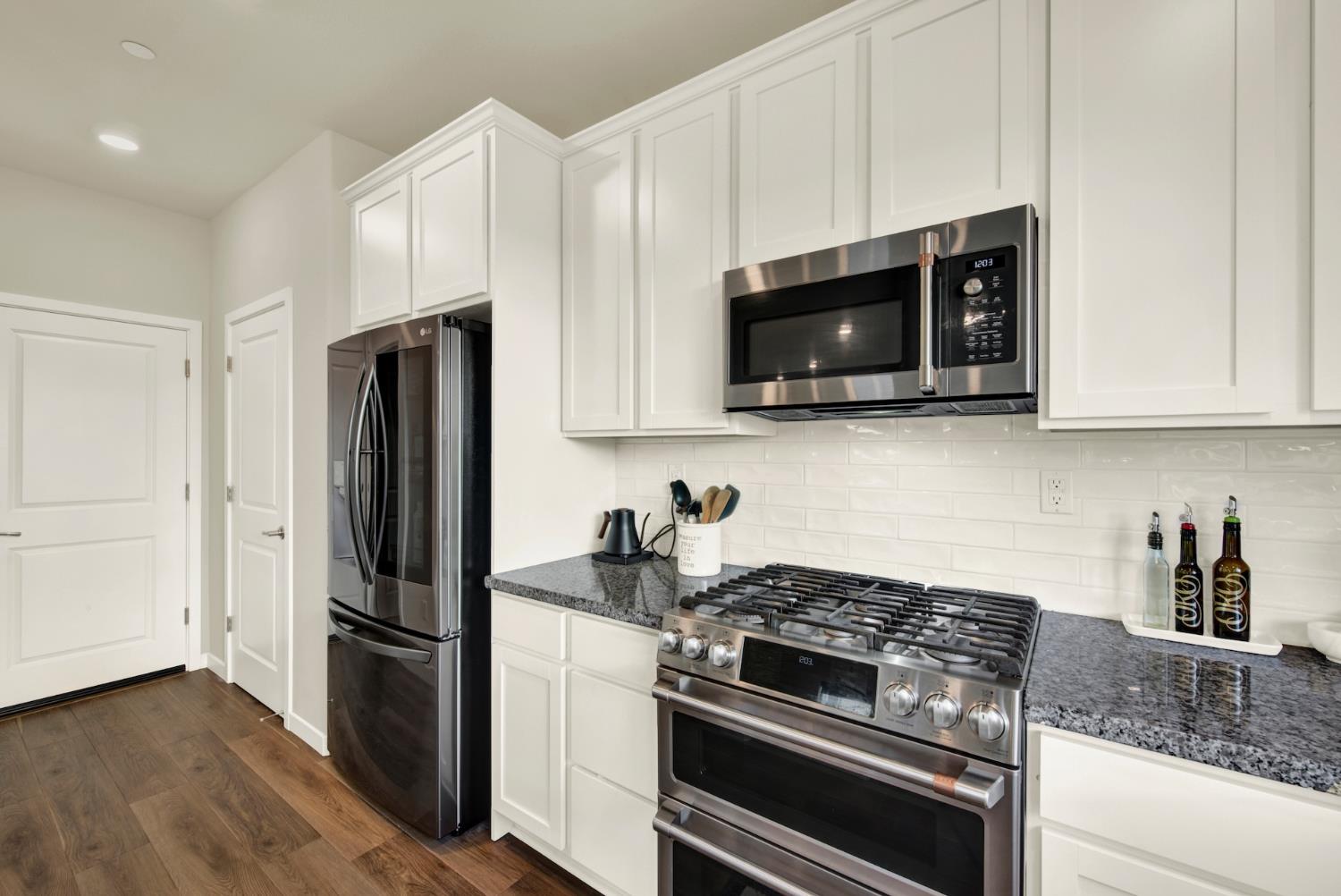 Kitchen with white shaker cabinets, granite counters, stainless appliances, and a gas range.