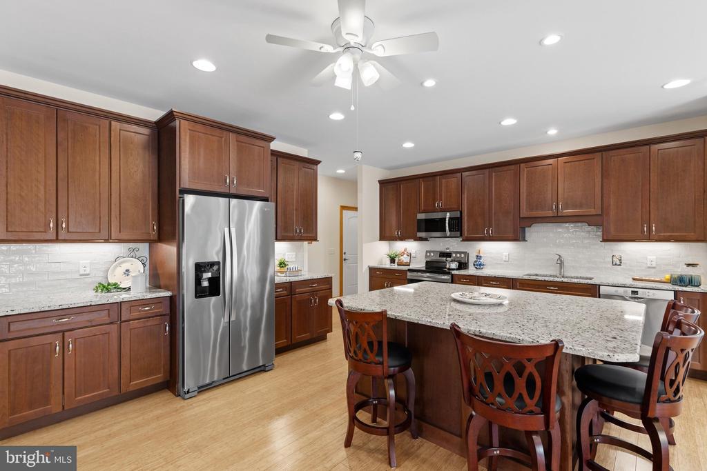 Kitchen with dark wood cabinets, stainless appliances, and a large granite island with bar seating.
