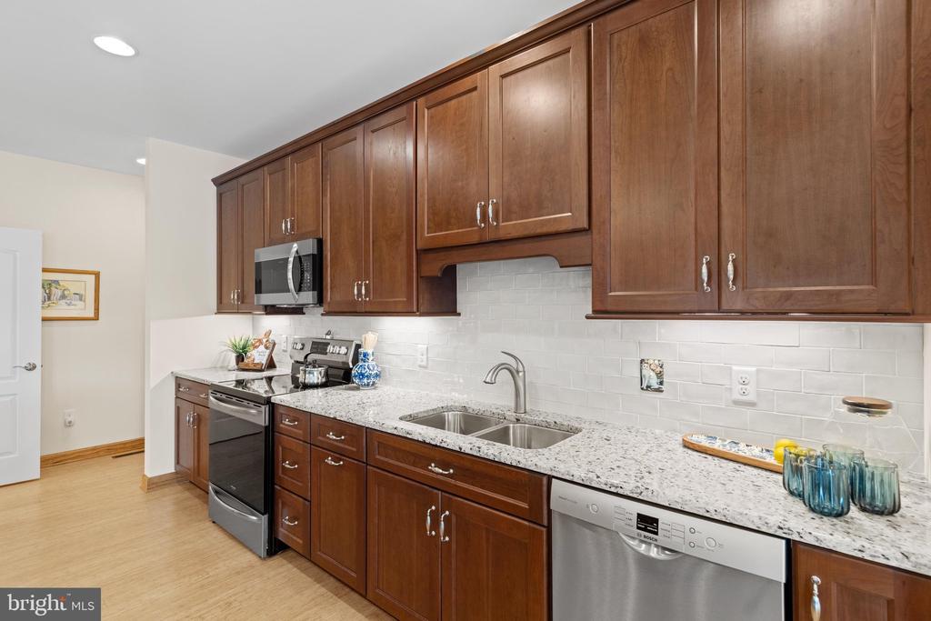 Kitchen with cherry cabinets, granite counters, white subway tile, and a double-basin sink.