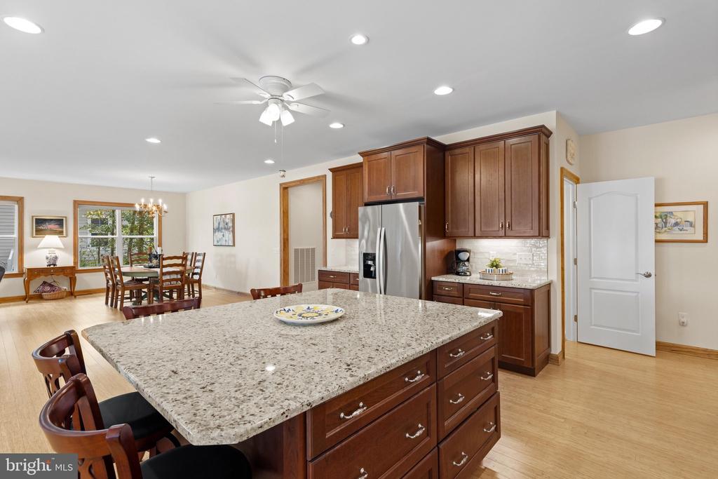 Kitchen with a large granite island, dark wood cabinetry, and stainless steel appliances.