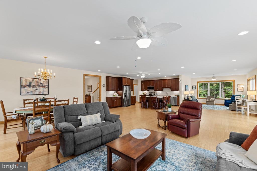 Open-plan living room with gray seating, hardwood floors, and a view into the kitchen and dining area.