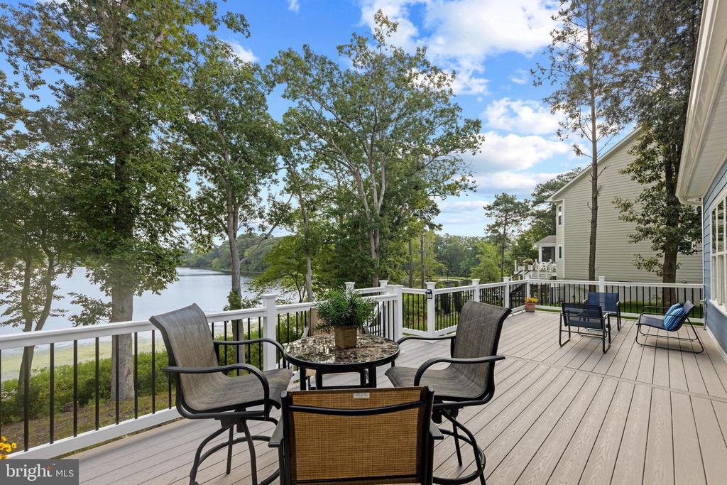 Furnished deck with an outdoor dining set and views across a wooded lake.