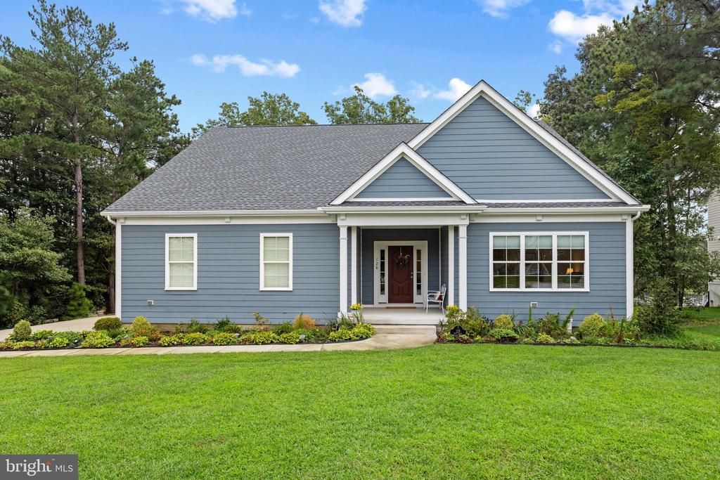 Blue-gray single-story home with a covered entry, red front door, and broad green lawn.