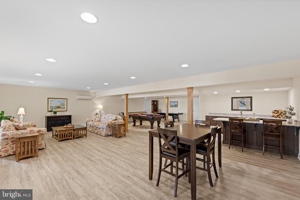 Furnished basement recreation room with a pool table, dining area, and bar counter.