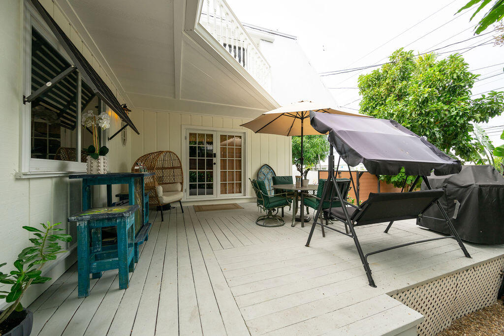 Furnished white deck with French doors, outdoor dining set, lounge chairs, and patio umbrellas.