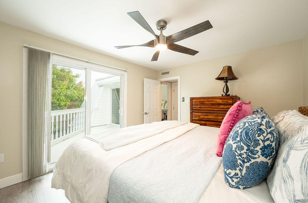 Bedroom with a white bed, colorful accent pillows, and sliding glass doors to a balcony.