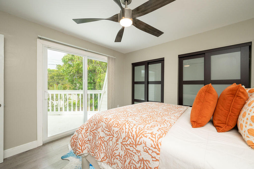 Bedroom with orange coral-patterned bedding, a ceiling fan, and a sliding glass door to a balcony.